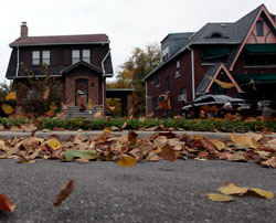 美国底特律一个维护得很好的小区里，准备拍卖的空房子（中）门前落叶纷飞。