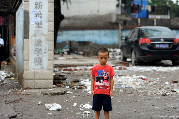 8月15日，北京，一名小男孩站在已经被夷为平地的校门口。 王苡萱/CFP  _农民工子弟学校遭拆迁 家长躺马路维权