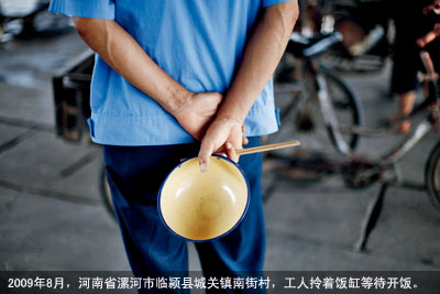 2009年8月，河南省漯河市临颍县城关镇南街村，工人拎着饭缸等待开饭。