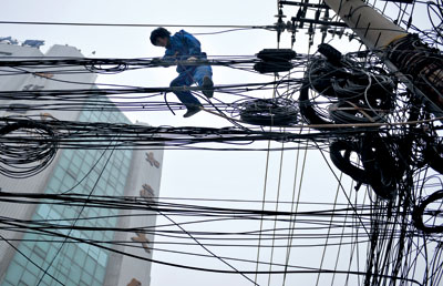 2012年2月28日，在陕西西安桥梓口，一家通信公司的工人爬上路边的电线杆，整理凌乱的通讯线缆。其工友称，架在空中的线缆有移动、联通、电信等多家运营商的，最多的地方近百根线缆纠结在一起，再加上预留的线缆，形成杂乱不堪的城市“蜘蛛网”。