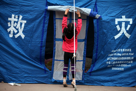 2013年4月21日，四川省雅安市芦山县上里镇，一个女孩卷起临时帐篷的门帘。