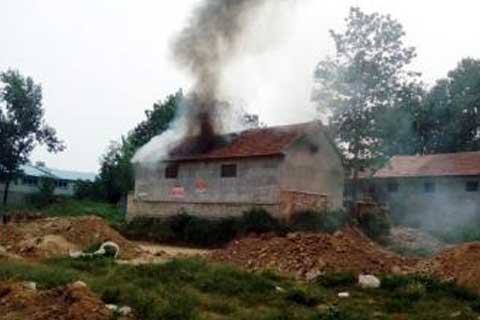 Smoke pours out of the Shandong Province home of Zhang Jimin on September 14. Zhang died in the fire