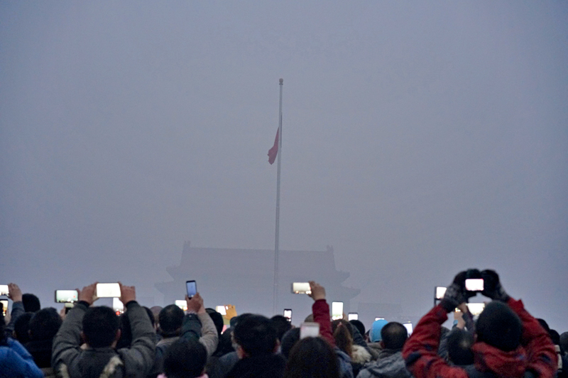 Tourists at Tiananmen Square to watch the daily flag-raising ceremony at sun rise, amid thick smog on December 1