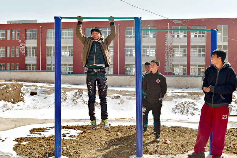 Wang Yongqiang who is testing his strength on the bar, dropped out of school in 2013 when he was 16 and says he plans to leave to work in a city