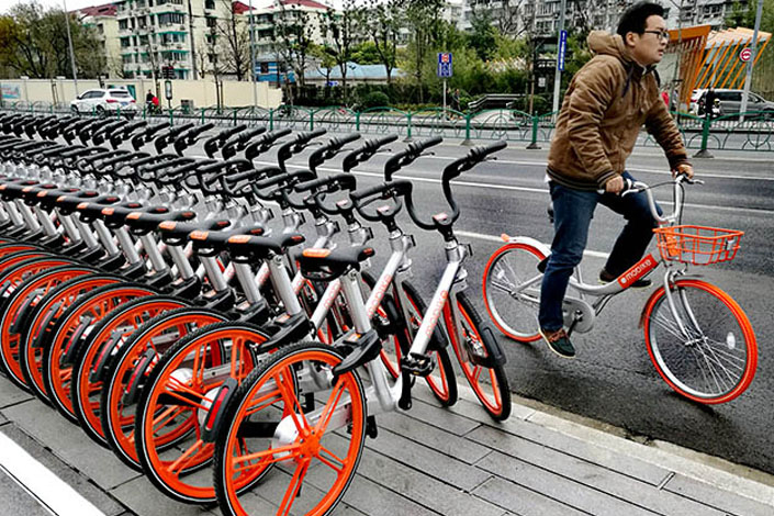 A man in Shanghai rides a Mobike Lite, a recent upgrade to the bicycle-sharing company's Classic Mobike model, such as those on the sidewalk, on Dec. 20. Photo: IC
