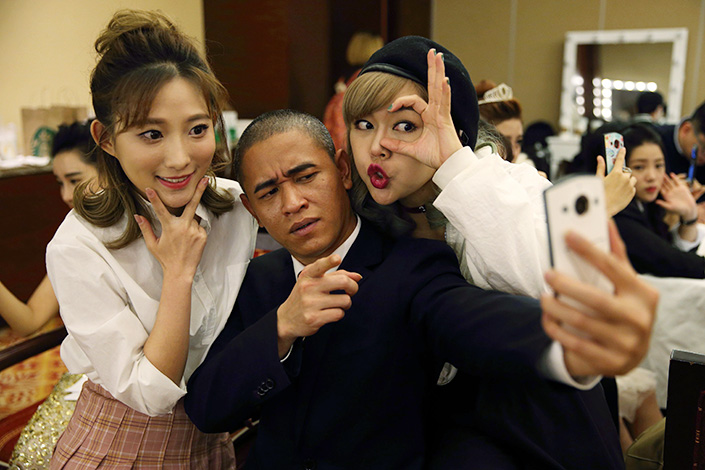Chinese actor Xiao Jiguo (center), famous for his striking resemblance to U.S. President Barack Obama, poses with two actresses for a selfie taken by a Meitu phone in Beijing on Oct 28. Meitu has announced that internet-related revenue growth was strong in December. Photo: Visual China