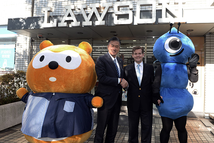 Genichi Tamatsuka (left), CEO of Lawson Inc., and Douglas Feagin, senior vice president of Ant Financial Services Group, pose with mascots in front of a Lawson convenience store in Tokyo on Monday. Customers can now use Ant Financial's online payment service, Alipay, in the approximately 13,000 Lawson stores in Japan without incurring fees for paying with Chinese yuan. Photo: Xinhua