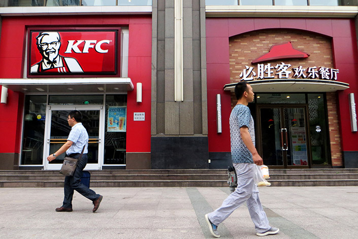 Pedestrians walk past neighboring KFC and Pizza Hut restaurants in Yichang, Hubei province, on June 6. Yum China Holdings Inc., which operates the two restaurant chains in the country, reported flat same-store sales and falling revenue in its maiden quarterly report, released in the U.S. on Tuesday. Photo: IC