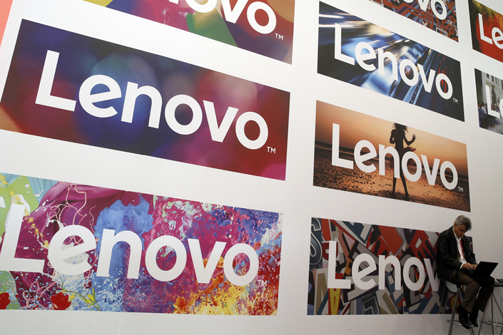 A man uses his laptop next to Lenovo logos during the Mobile World Congress in Barcelona, Spain, on Feb. 25, 2016. Lenovo said on Friday it will sell 49% of a China property joint venture as it continues to struggle with poor performances from its non-PC businesses. Photo: Visual China