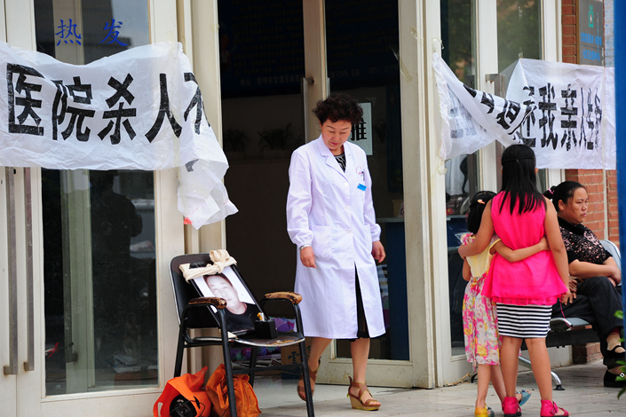 Family members of a man who died in a hospital in Kunming, Yunnan province, stage a protest while trying to block the door of the hospital on Aug. 27, 2015. The banner says 