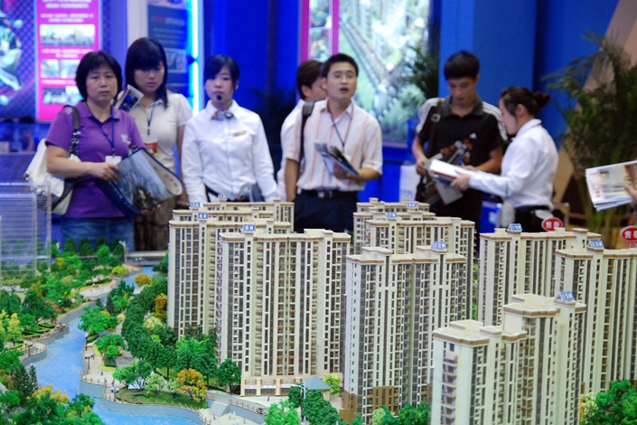 Sales staff present real estate information to prospective buyers in Qingdao, Shandong province, on Sep. 5, 2010. Nanjing, Qingdao and Ganzhou issued home-purchase curbs to rein in speculation in the housing market. Photo: Visual China