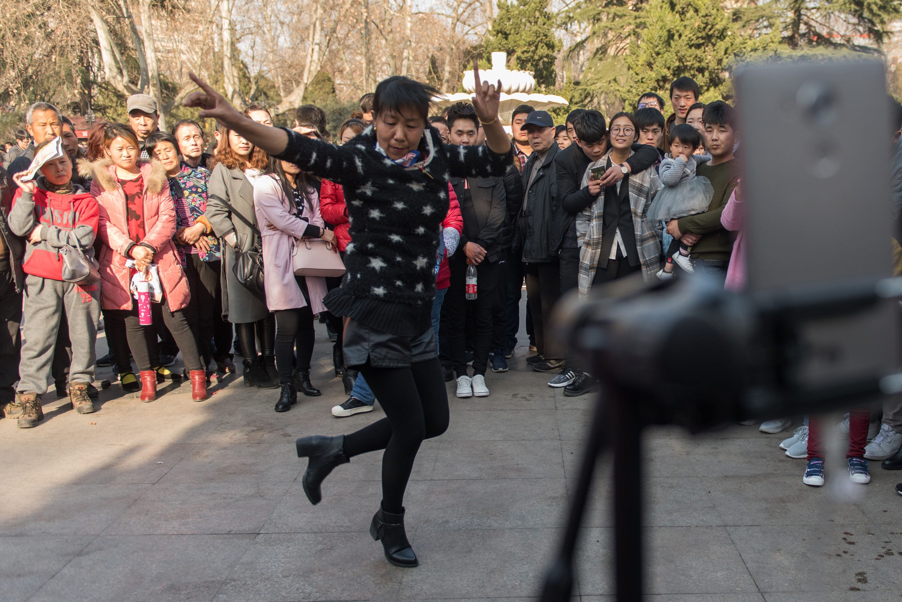 Wang Lingzhi performs in front of a crowd and a live-streaming smartphone. She is known as Grandma Two Pistols, as she often holds her hands in the shape of two pistols. Photos: Chen Liang/Caixin