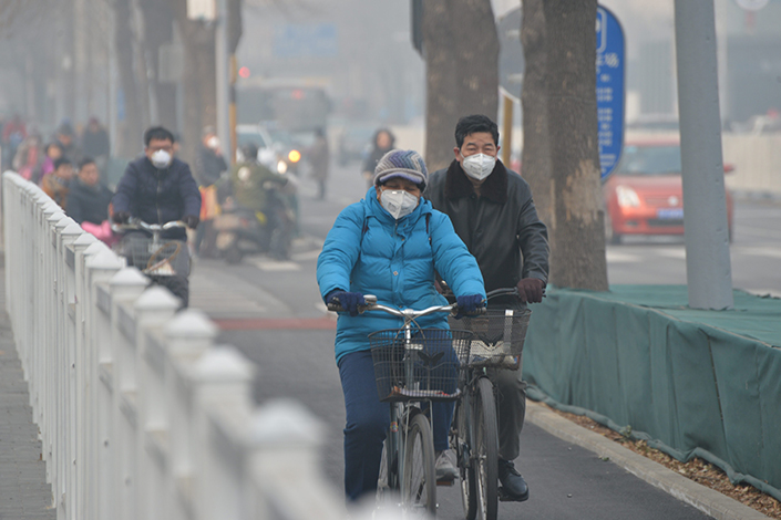 Bicyclists ride along Beijing's smog-shrouded Wangfujing Street on Dec. 31. The Ministry of Environmental Protection said the concentrations of PM2.5 and PM10 particulate matter in the Beijing-Tianjin-Hebei area rose sharply year-on-year in the first three months of 2017.  Photo:IC
