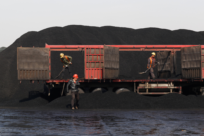 Workers move coal to a transport vehicle in Tianjin on Wednesday. Tianjin has banned polluting diesel-powered coal trucks from its port three months ahead of schedule. Photo: Xia Weicong/Caixin