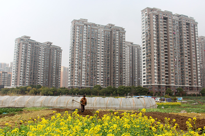 The Ministry of Land and Resources said Monday that average residential land price in China increased 7.91% in 2016, up nearly 4 percentage points from a year earlier. Above, a farmer works near residential real estate in Changzhou, Jiangsu province, on March 25. Photo: Visual China