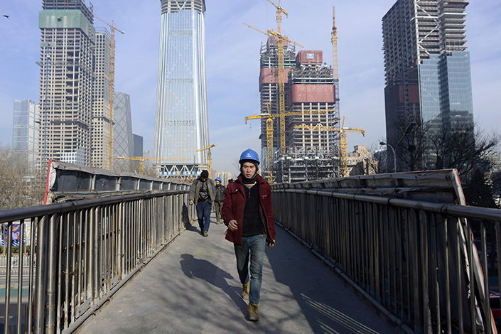 A workman crosses a bridge in Beijing on Dec. 16, 2016. Property investment in the Chinese capital is falling as government curbs on home purchases take effect. Photo: Visual China