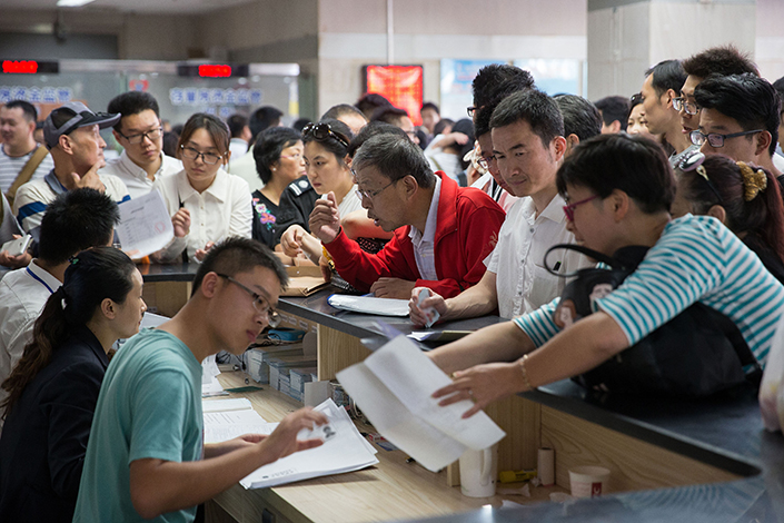 The Nanjing city government says graduate-degree holders, skilled technicians and professionals working in the city now will be excluded from a promise that they would be eligible to buy a home after paying income taxes and social security fees for five years. Above, Nanjing residents conduct housing transaction procedures in a real estate registration center in the city on Sept. 26. Photo: Visual China