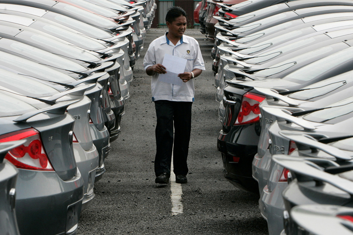 Chinese company Geely has recently bought a major stake in Malaysian carmaker Proton and its sports car subsidiary Lotus. Above, a worker checks Proton cars at a car lot near Kuala Lumpur, Malaysia, on Jan. 12, 2009. Photo: Visual China