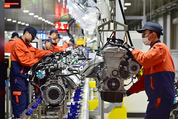 Chinese regulators will strictly limit construction of new car manufacturing plants in a bid to rein in a runaway buildup. Above, workers assemble engines in a car production line of Zhejiang Geely Holding Group in Yiwu, Zhejiang province, on Feb. 7. Photo: Visual China