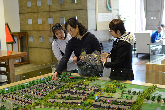 The government of Beijing has eased permitting rules to allow real estate developers to sell more units before completing construction on residential projects. Above, prospective homebuyers look at a model of a residential development in Beijing’s Shunyi district. Photo: Visual China