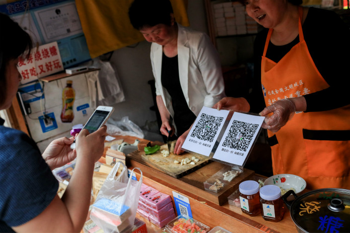 Tencent’s new service will allow users to earn interest from their WeChat balances. Above, a customer uses her smartphone on May 15 to pay at a store in Shanghai that accepts payment via WeChat and rival Alipay. Photo: Visual China