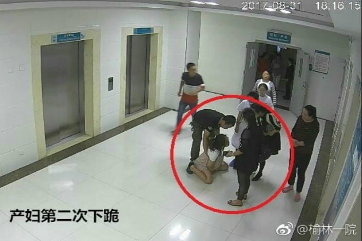 A video screen grab from the First Hospital of Yulin in Shaanxi province shows 26-year-old Ma Rongrong kneeling in front of her family in a hospital hallway on Aug. 31. The video has no sound so it is unknown whether she was kneeling in pain or begging the family for permission to let her have a cesarean section. Ma later committed suicide by jumping out of a fifth-floor window at the hospital.Photo: First Hospital of Yulin
