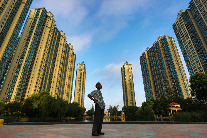 Several companies that manage rental apartments are working with regulators over the issuance of securities, particularly real estate investment trusts, backed by home rental properties. Above, high-rise residential buildings tower above a passer-by on Sept. 1 in Jiangsu province. Photo: Visual China
