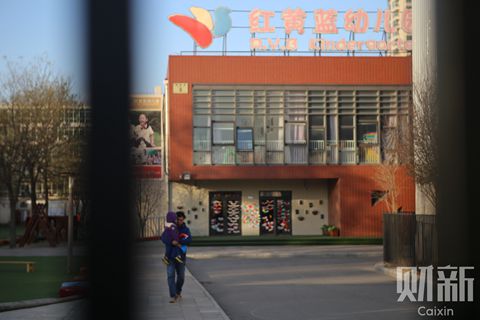 A parent on Thursday carries his child on his way out of the Beijing kindergarten accused of abusing children. The company that runs the facility directly operated 80 kindergartens and franchised another 175 preschools, in 130 cities and towns across China, as of June 30. Photo: Chen Weixi/ Caixin