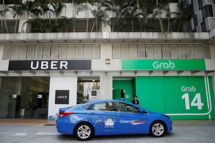 A ComfortDelGro Corp. taxi drives by the offices of Uber and Grab in Singapore on Monday. Photo: VCG
