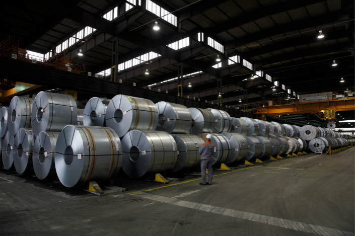 A worker stands beside rolls of steel before they are shipped from the Salzgitter AG plant in Salzgitter, Germany on March 22. Photo: VCG