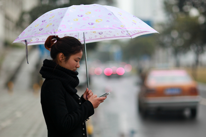 A woman uses her phone to book a taxi on a street in Zhuzhou, Hunan province. Photo: VCG