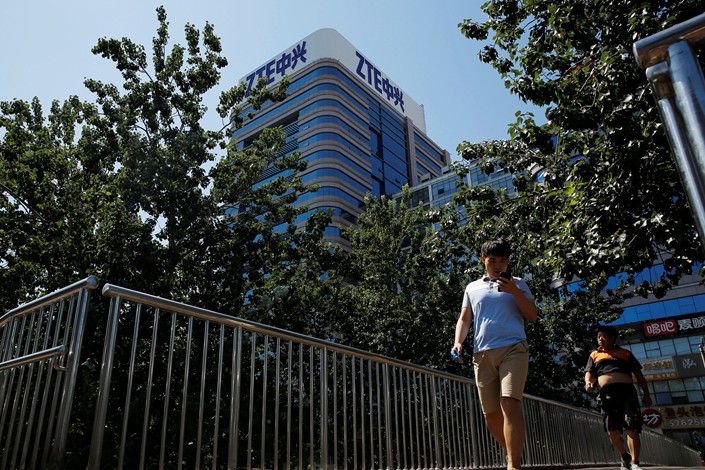 People walk past a ZTE Corp. building in Beijing on Aug. 29.  Photo: VCG