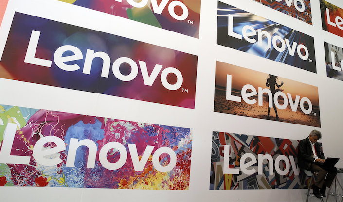 A man uses his laptop next to Lenovo's logos during the Mobile World Congress in Barcelona, Spain February 25, 2016. Photo: VCG