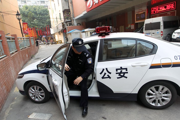 A Guangzhou police officer steps out of his patrol car. Photo: VCG