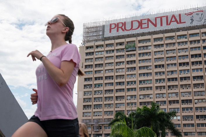 A woman runs past as a banner featuring the Prudential PLC logo in Hong Kong on Aug. 9. Photo: VCG