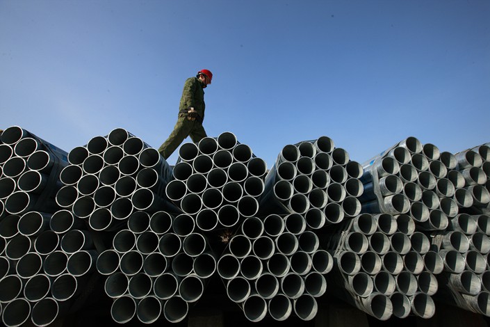 A worker walks across seamless steel pipes produced in Huaibei, Anhui province on Dec. 18, 2017. Photo: VCG