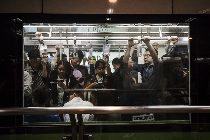Passengers on a crowded Shanghai subway train focus on their phones on Oct. 13, 2017, Photo: VCG