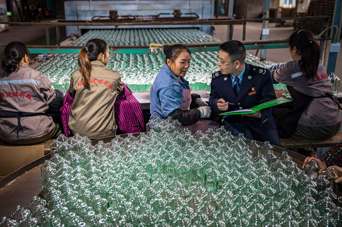 Staff of a local tax bureau in the western city of Chongqing work a shift at a glass bottle factory to better understand how the production process works. Photo: VCG
