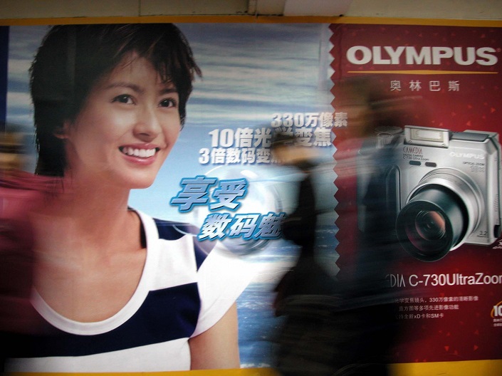 Pedestrians walk past an ad for Olympus cameras in Beijing in 2003. Photo: VCG