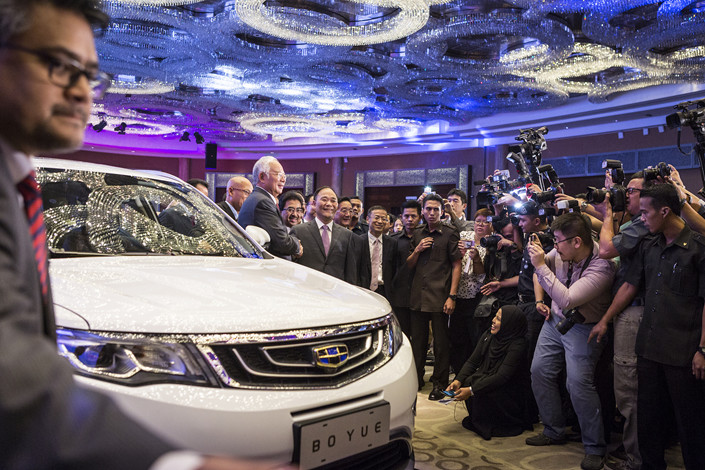 Then-Malaysian Prime Minister Najib Razak (behind side view mirror)  shakes hands with Li Shufu, chairman of Zhejiang Geely Holding Group Co. Ltd., next to a Geely Boyue SUV during a signing ceremony between DRB-Hicom Berhad and Geely in Kuala Lumpur, Malaysia, in June 2017. Photo: VCG