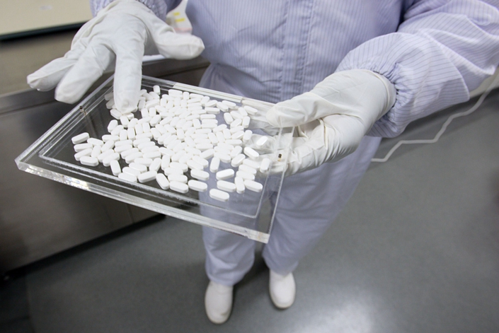 A Merck technician inspects a tray of Vytorin pills, the pharmaceutical company's new cholesterol-lowering drug, at the end of the production line at their Singapore manufacturing facility in August 2004. Photo: Bloomberg