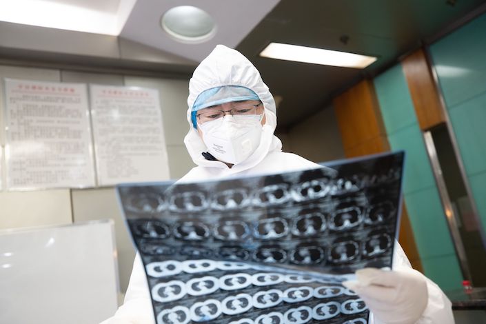 A doctor examines the chest scan results of a Covid-19 patient. Photo: Caixin