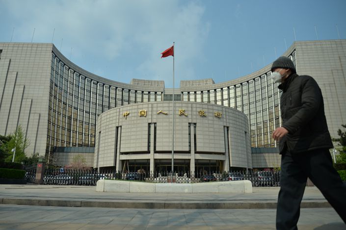 A man wearing a mask walks past the headquarters of the People's Bank of China in Beijing as the country is hit by the Covid-19 outbreak. Photo: VCG