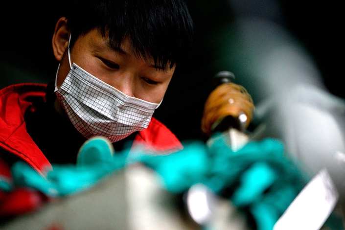 A worker wears a face mask as he makes insoles a factory in Wenzhou, Zhejiang province, on Feb. 27. Photo: Bloomberg