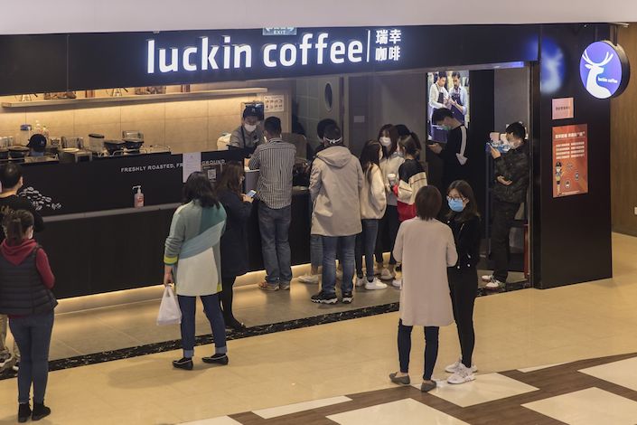 People wearing protective masks wait at a Luckin Coffee Inc. outlet in Shanghai. Photo: Bloomberg