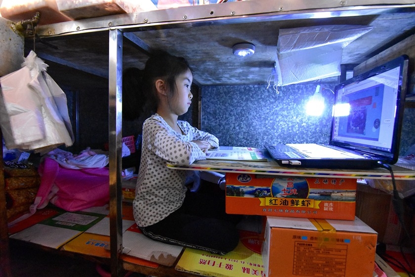 Ke Enya, 7, takes an online class from a makeshift desk under her parents&a...