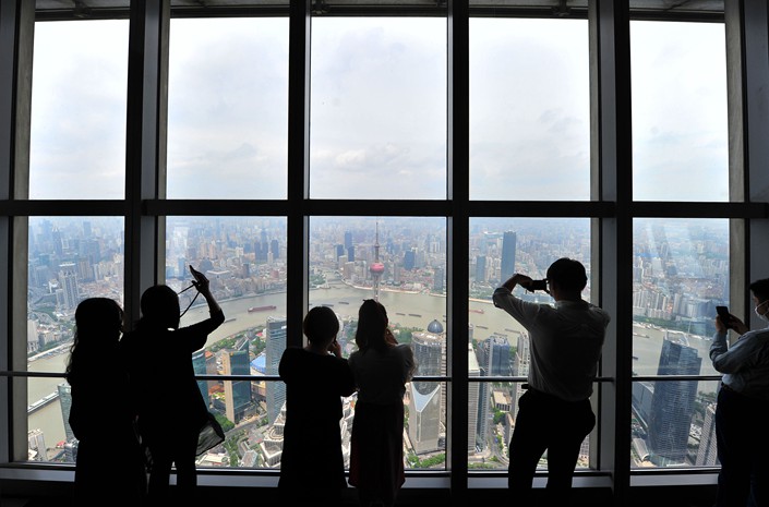 Tourists take photos from the heights of the Shanghai World Financial Center in Shanghai on May 15.