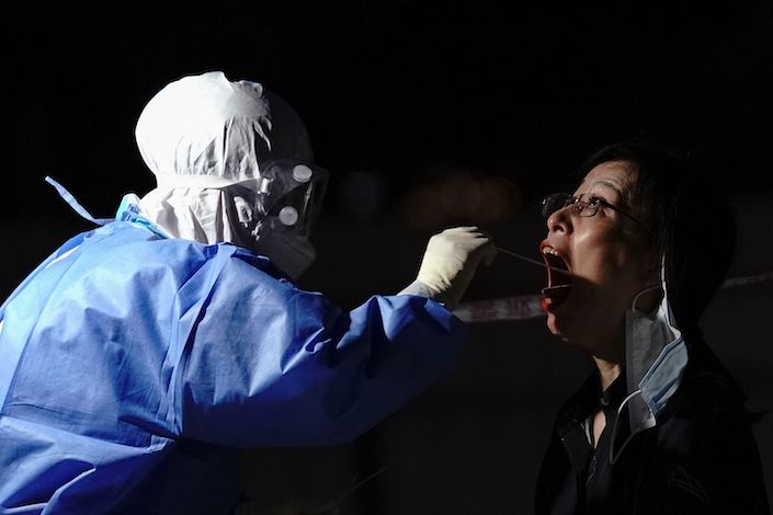 A medical worker wearing a protective suit takes a swap at a temporary test station on July 6, 2020 in Beijing. Photo: Bloomberg
