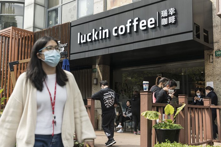 People wearing protective masks gather outside a Luckin Coffee Inc. outlet in Shanghai on  April 3. Photo: Bloomberg