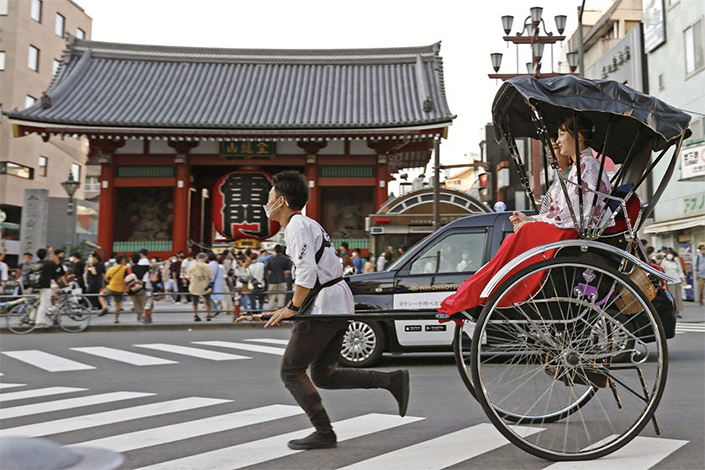 Visitors in traditional Japanese costumes take a ride on a rickshaw in Tokyo, Japan, on Sept. 21.